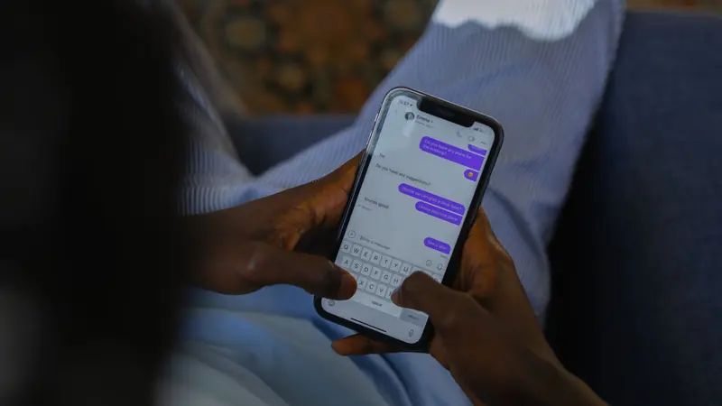 Manos sostienen un celular con una conversación de chat llena de mensajes